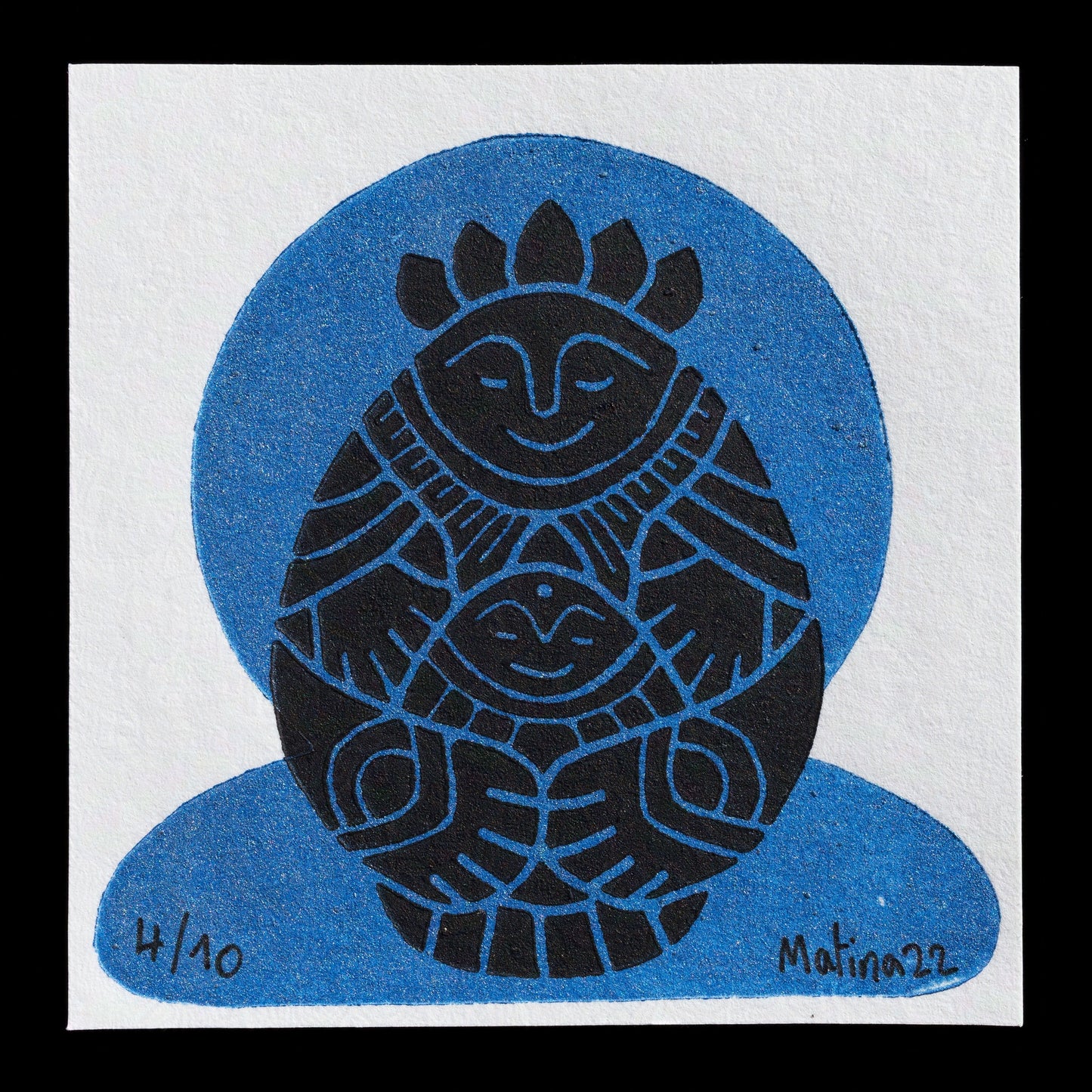 The artwork "Untitled" by Matina showcases a distinctive blue circle with a black design at its center, featuring a stylized face and geometric patterns. The artist's signature, "Matina22," is discreetly placed in the bottom-right corner of the print.