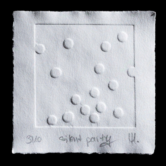 This photograph captures a white paper with raised dots, featuring a square-shaped blind embossing. The title 'silent party' is inscribed at the bottom of the image in pencil. A TetraPak box is used as an alternative to traditional printing plates, creating a unique and textured effect on the paper.