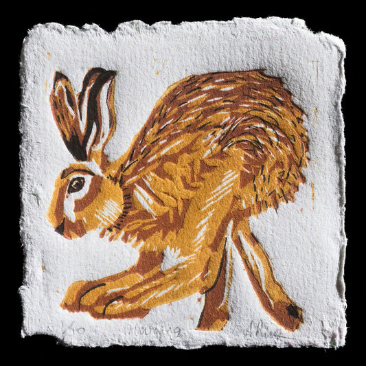 Here is a short SEO description of the print:

**Title:** Haring
**Artist:** Andrya Prescott
**Techniques:** Linocut
**Description:** A captivating linocut print featuring a stylized hare in warm, earthy tones on a textured white background.