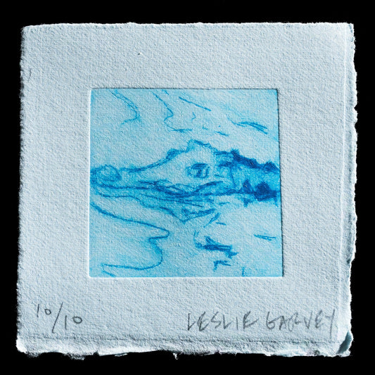 This captivating drypoint intaglio print titled "Snap" by Leslie Garvey showcases a striking blue abstract design on light blue paper, evoking an aerial perspective reminiscent of landscape or seascape elements. The artist's signature is discreetly inscribed at the bottom edge in pencil.