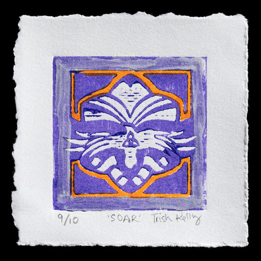This linocut print titled 'Soar' by Trish Kelly showcases a captivating design featuring an open book with wings, symbolizing freedom and knowledge. The dominant purple hue is complemented by orange accents, adding depth to the composition.
