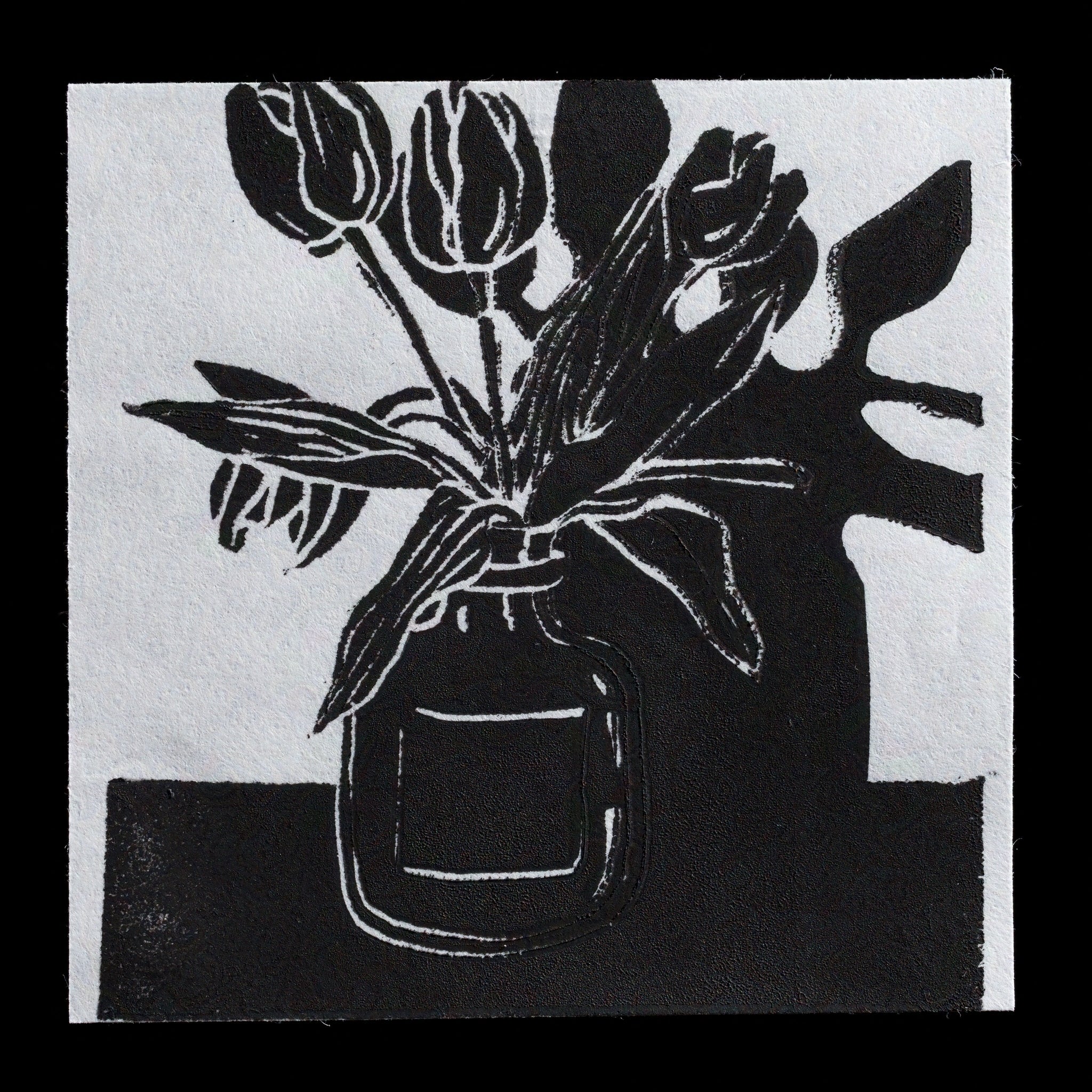 This monochromatic linocut print by LeHuong features a simple yet striking composition. Against a stark white background, three tulips stand out in bold black lines, while their stems and leaves are rendered in subtle gray tones. The arrangement is set against a dark, rectangular shape on the right side of the image, creating a sense of depth and contrast.