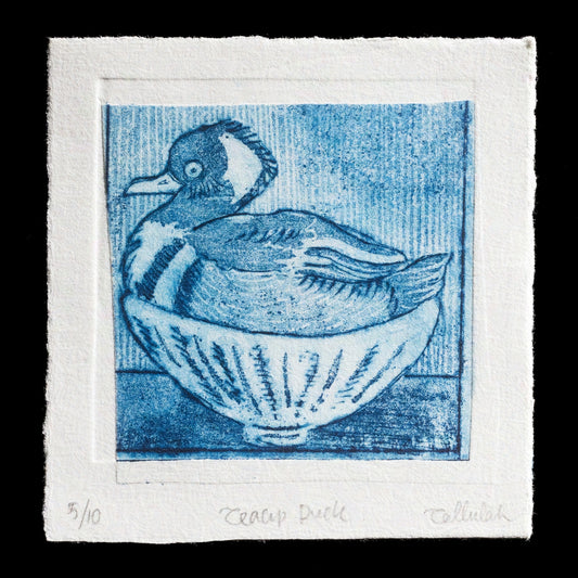 This monochromatic etching, 'Teacup Duck' by Tallulah Cunningham, showcases a duck nestled in a teacup, rendered in deep blue hues against an equally dark background. The artwork's simplicity is offset by intricate details and textures, evoking a sense of whimsy.