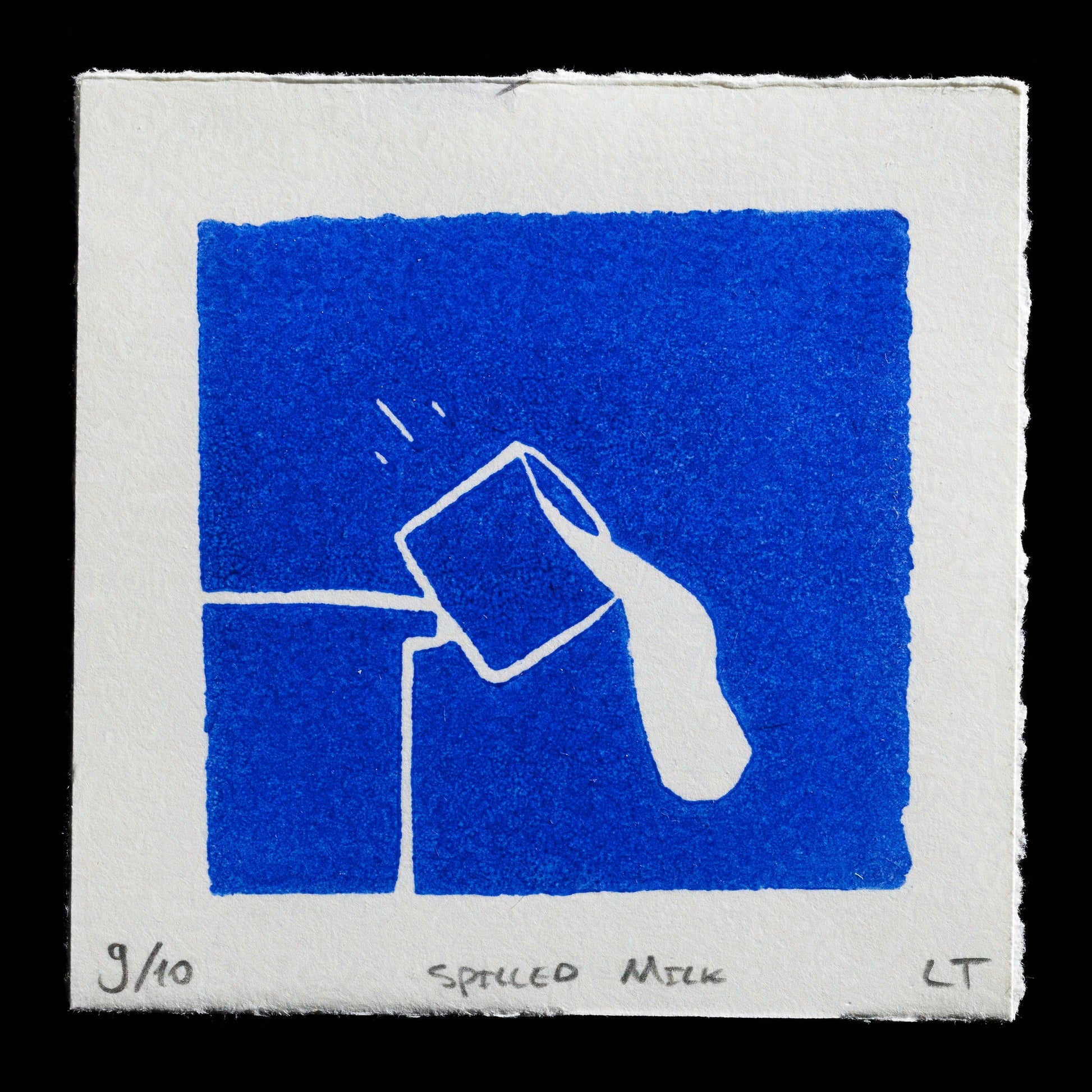 This artwork is a linocut titled 'Spilled Milk' by Lea Krause & Thom Pijnenburg. It features a simple yet evocative design in a striking blue hue, with a white outline of a milk carton and spilt liquid on a plain background. The print's edges have been intentionally torn along the paper's fibers, adding texture to its minimalist aesthetic.