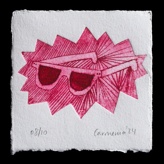 This captivating etching, "SUNGLASSES" by Carmenia Moreno, showcases a vibrant red-and-pink palette against a white background. The artwork features bold, graphic sunglasses with angular frames and triangular lenses, set against a textured surface reminiscent of fabric or paper. The overall effect is a striking visual representation of the iconic accessory, inviting viewers to appreciate its simplicity and elegance.
