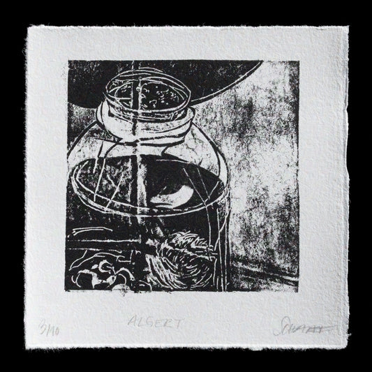 This print, 'Algert' by Joan Schaaf, showcases a striking black and white composition featuring a glass jar with lid, an abstracted face, and other indistinguishable objects in a monochromatic palette. The artist's use of TetraPak techniques creates a textured, almost three-dimensional effect on the paper surface, adding depth and visual interest to the piece.