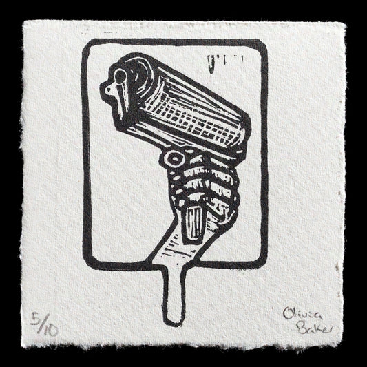 This print by Olivia Baker is titled "Print Isn't Dead" and showcases a captivating linocut technique. The artwork features a stylized hand grasping a popsicle cone, set against a light grey background with black outlines and accents. The print's visible content and colors are characterized by its bold lines, simple composition, and playful subject matter, making it an intriguing piece for art enthusiasts.
