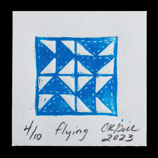 This artwork, titled "Flying" by Candra K. Gill, showcases a striking blue linocut design featuring geometric shapes arranged in a symmetrical pattern against a white background.