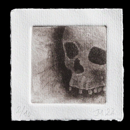 This monochromatic etching, titled "Skull" by Jess Milhausen, showcases a detailed skull rendered in black ink on textured white paper. The drypoint technique creates subtle texture, while mezzotint adds depth and dimension to the image. The artist's use of black ink against a stark white background draws attention to the intricate details of the skull's features.