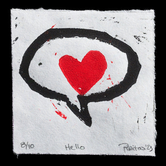 This print, titled 'Hello' by Pirita Paananen, showcases a striking design featuring a black speech bubble with a red heart at its center, set against a white background. The linocut technique is evident in the bold lines and textures of the print.