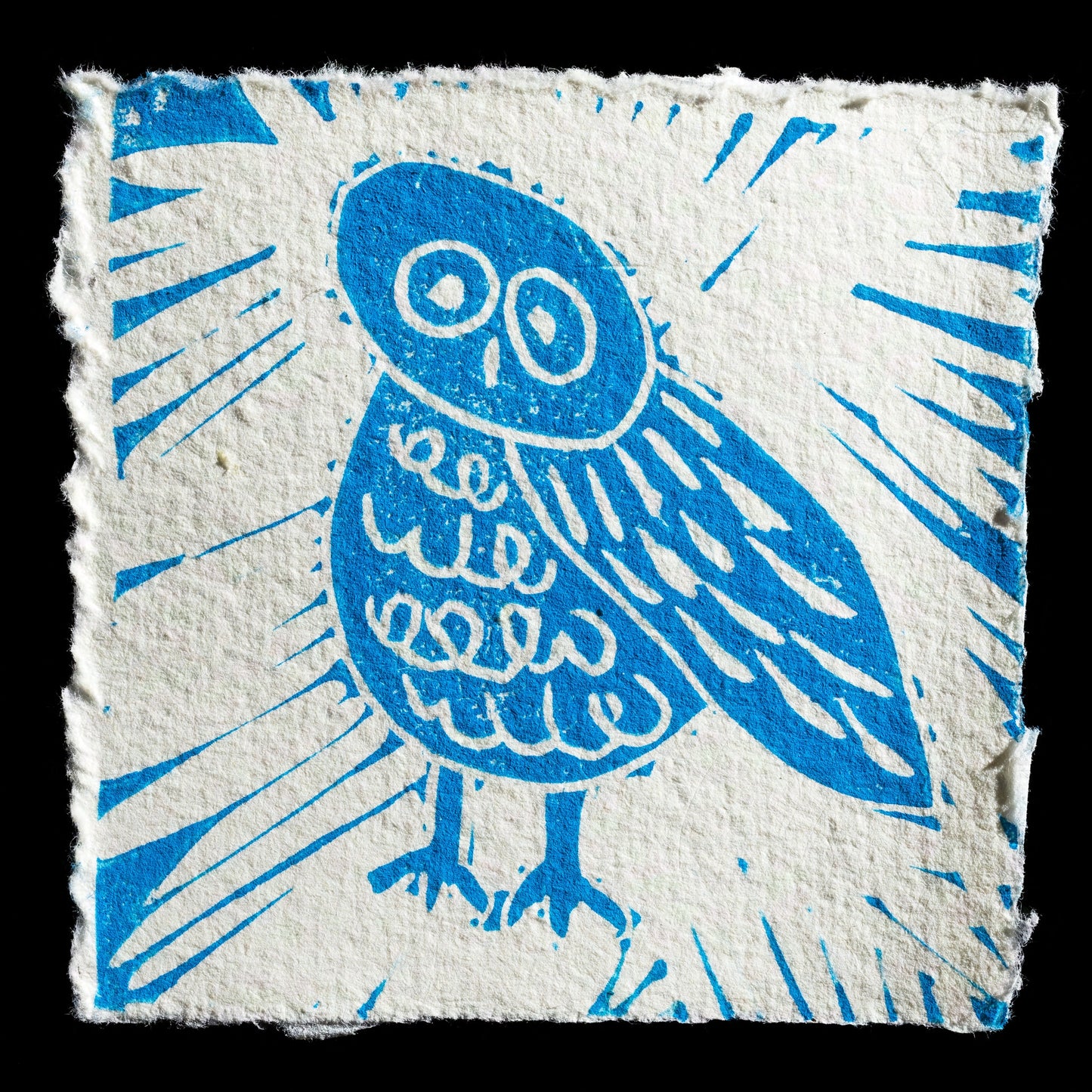 This captivating linocut print, titled "One Owl" by Jessamy Harvey, features a striking blue owl set against a white background, surrounded by abstract sunburst shapes in matching tones. The artwork's clean lines and vibrant color scheme evoke a sense of whimsy and playfulness, inviting the viewer to appreciate its unique charm.