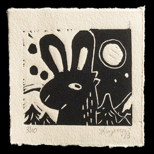 This linocut print, titled 'Rabbit Season,' features a stylized rabbit in black ink on a beige background with black lines and circles. The image showcases the artist's unique blend of minimalism and expressive style.