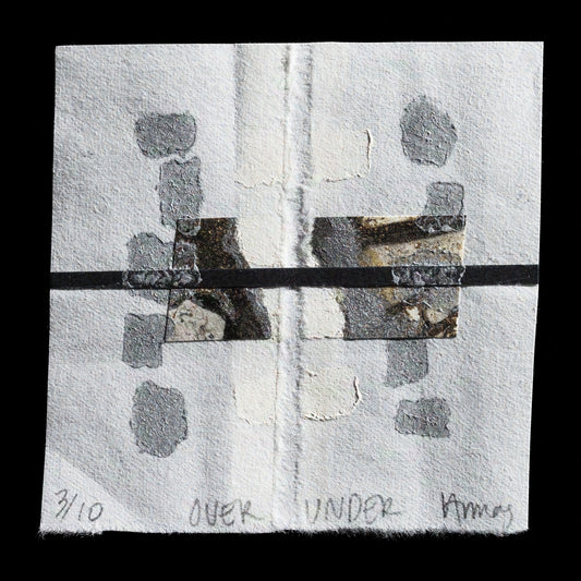 This abstract print, titled 'Over Under', is a collagraph artwork by Victoria Ballas Armas. It features a predominantly white composition with subtle grey and black accents. The arrangement showcases rectangular shapes in varying sizes, while smaller irregular forms are scattered throughout the background. A central horizontal line separates the composition into two distinct sections.