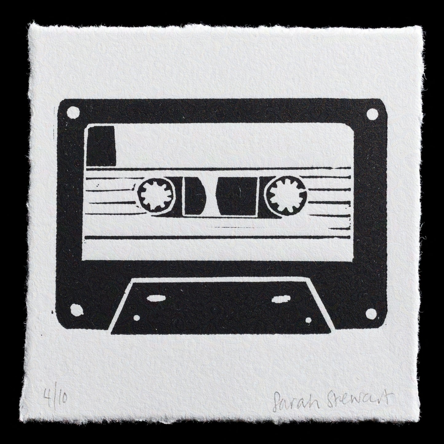 This linocut print, 'A-Side' by Sarah Stewart, features a stylized cassette tape design in black ink on white paper. The print is signed "4/10" in pencil at the bottom left corner, indicating its edition number. A handwritten note at the bottom right reads "Sarah Stewart".