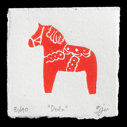 This captivating print, "Dala" by artist Petja Novak, showcases a Dala horse in bold red against a white background. Crafted using linocut techniques, the artwork features intricate details that bring this iconic Swedish symbol to life. The striking contrast between the vibrant red and crisp white creates a visually appealing piece.