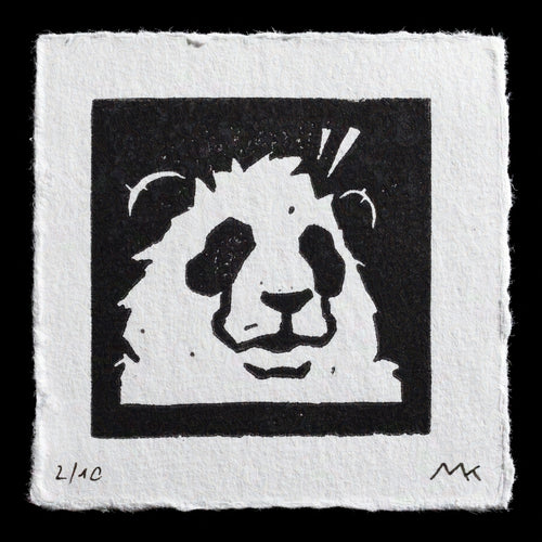 This linocut print features a stylized panda design in black ink on white paper. The panda's face is centered, with bold lines creating its distinctive features. A thick border surrounds the image, adding depth to the composition. The artist's signature and edition number are discreetly placed at the bottom corners of the print.