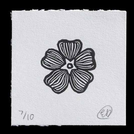 This monochromatic linocut print features a stylized flower with five petals, each adorned with thin black lines radiating from the center. A small circle marks the middle of the flower, set against a white background.

Created by Emily Dye, "Peters Mountain Mallow" showcases her skillful use of linocut techniques to produce this intricate design.