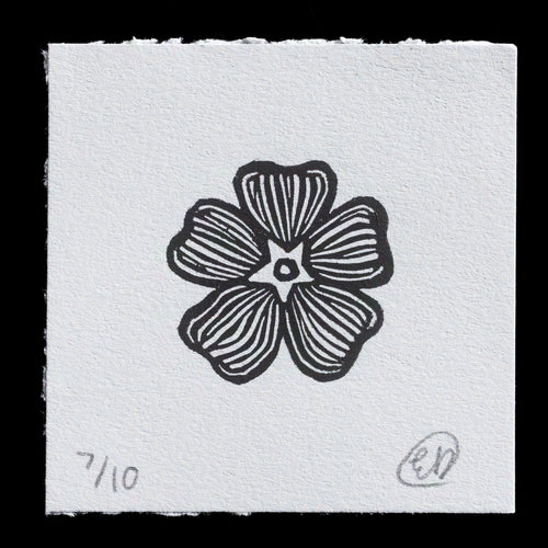 This monochromatic linocut print features a stylized flower with five petals, each adorned with thin black lines radiating from the center. A small circle marks the middle of the flower, set against a white background.

Created by Emily Dye, 